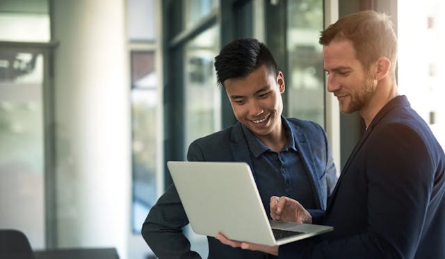 Two employees looking at a laptop 1200x699