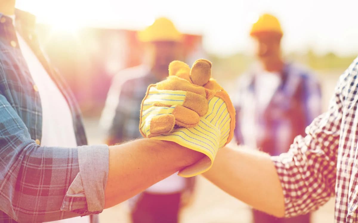 Two construction workers gripping hands