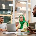 Three employees talking around a laptop