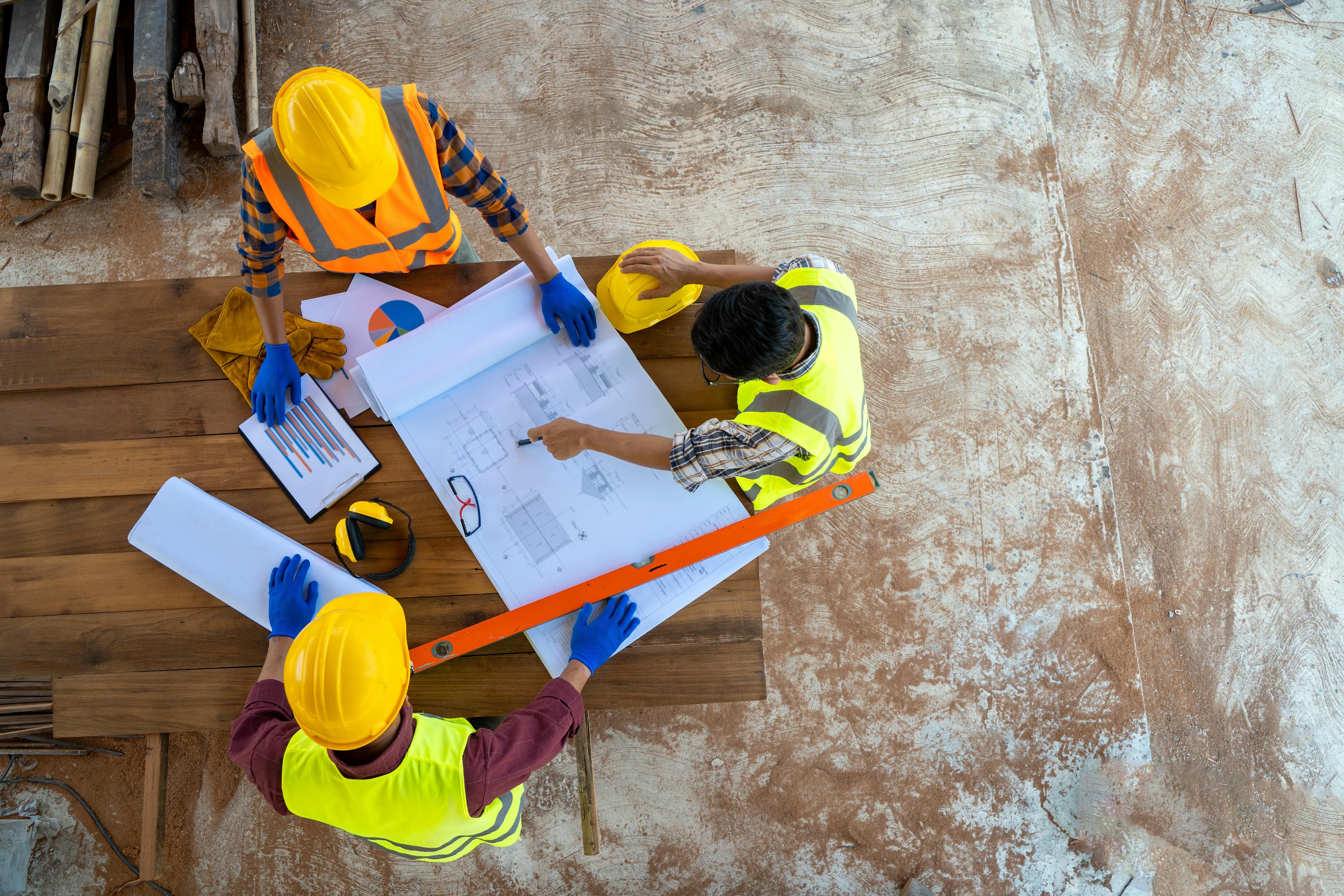 Over head shot of three construction workers standing looking at a drawing