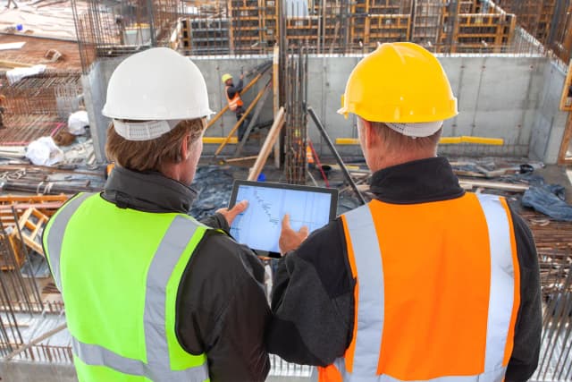 Two construction workers looking at an iPad