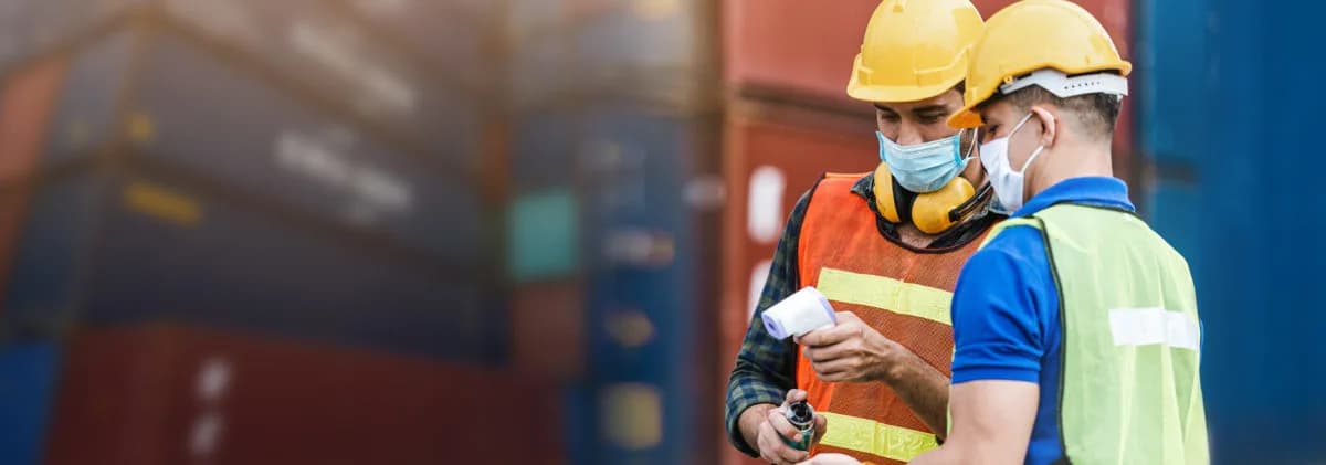 Two male construction workers in front of shipping containers 1200x421