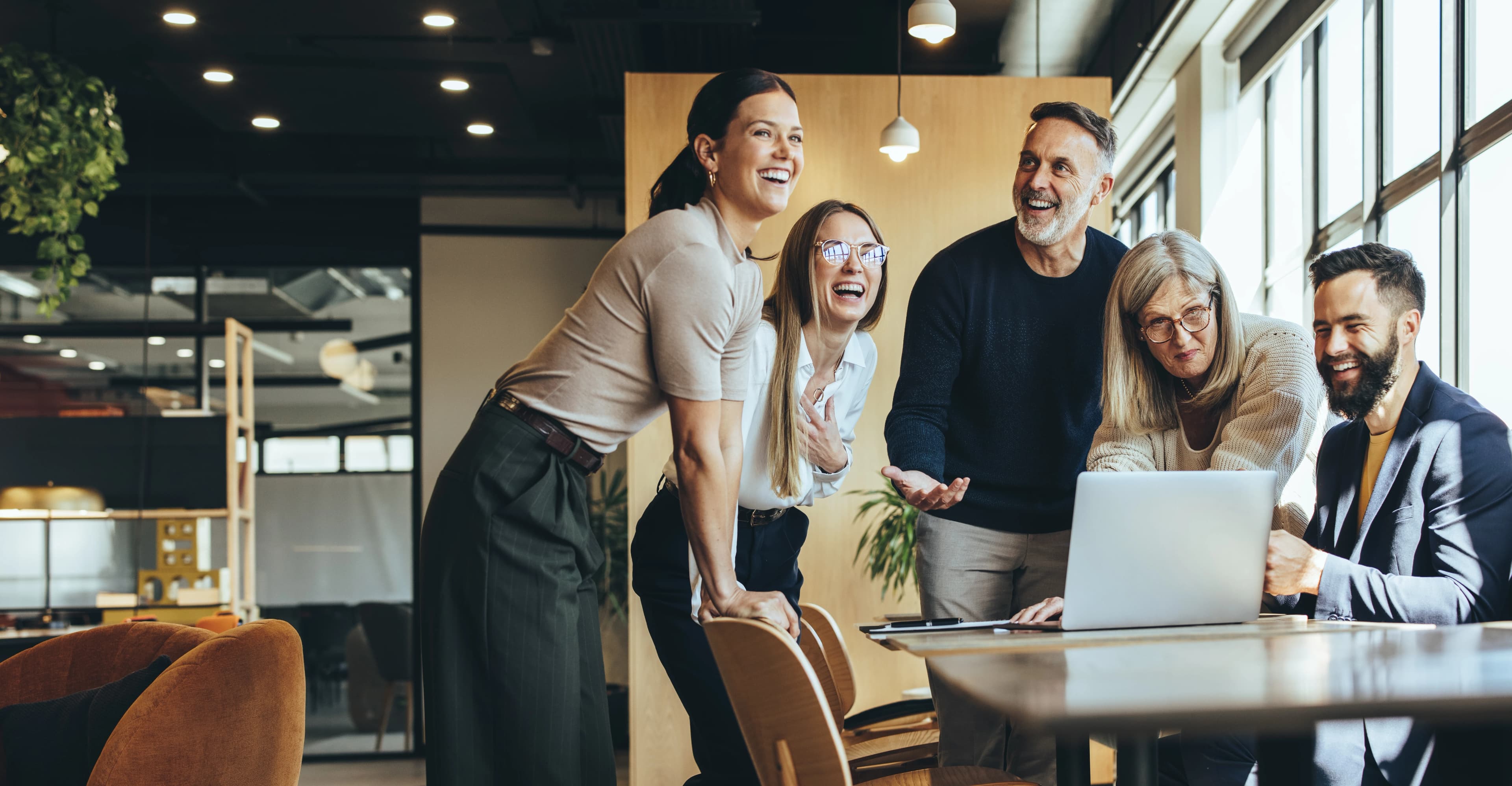 Five employees happy around a laptop