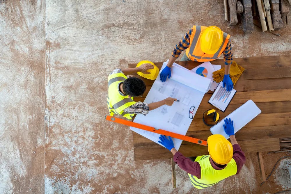 Three construction workers overhead shot looking at drawings