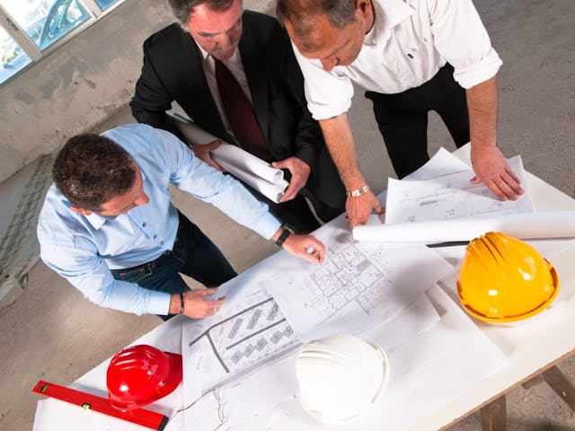 Three construction executives looking at drawings 1200x900