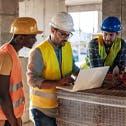 3 construction workers looking at a laptop