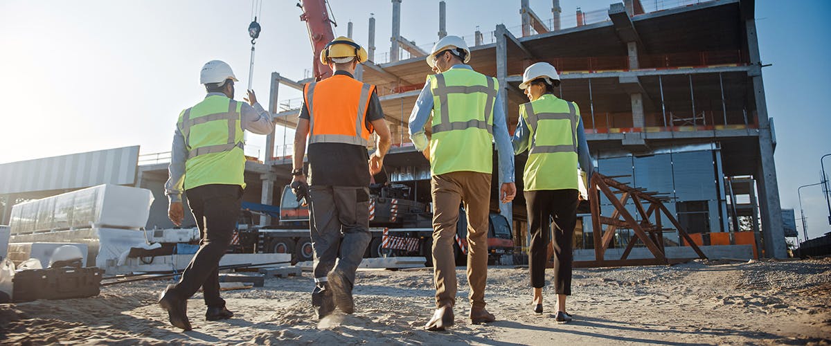 Four construction workers walking at a construction site