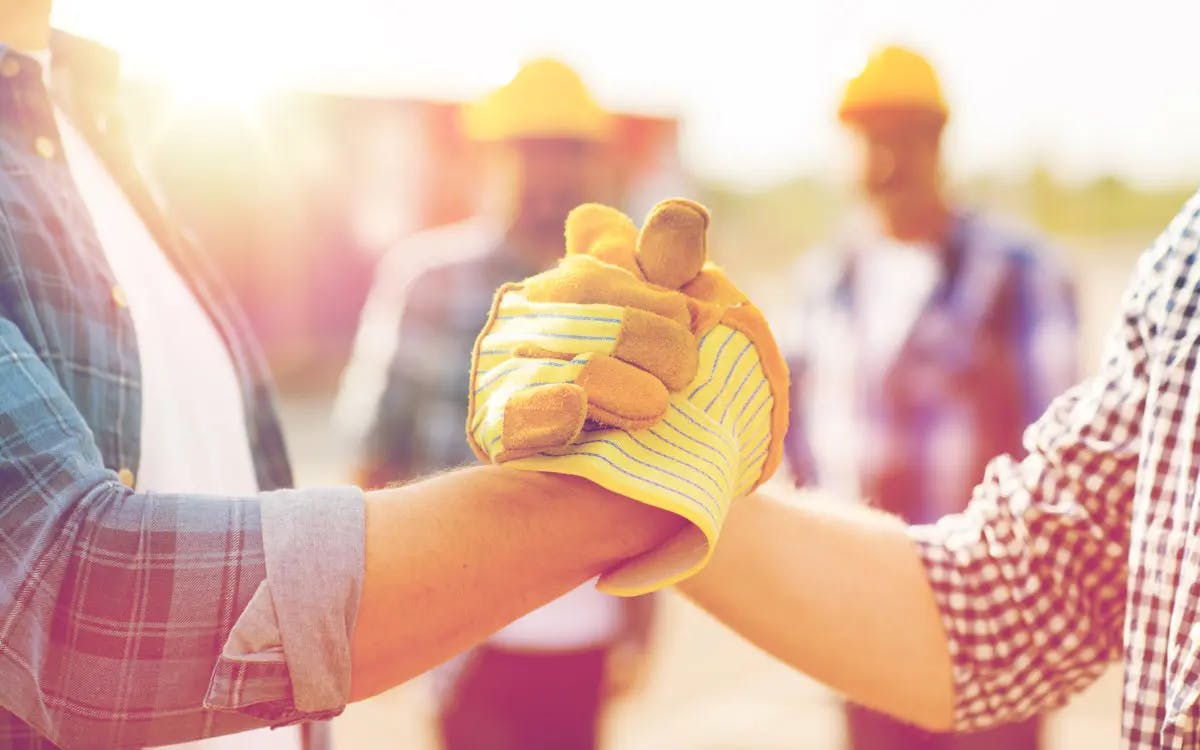 Two construction workers gripping hands