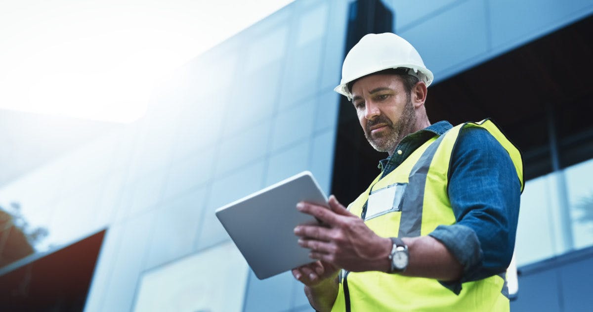 Male construction worker looking at an iPad 1200x631