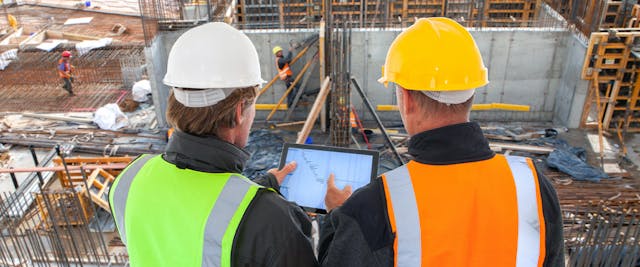 Two construction executives at a construction site looking at an iPad