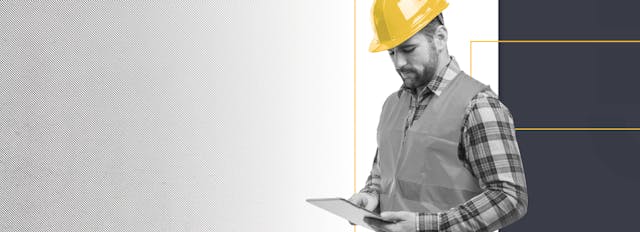 Male construction worker wearing yellow helmet looking at an iPad - black and white and yellow