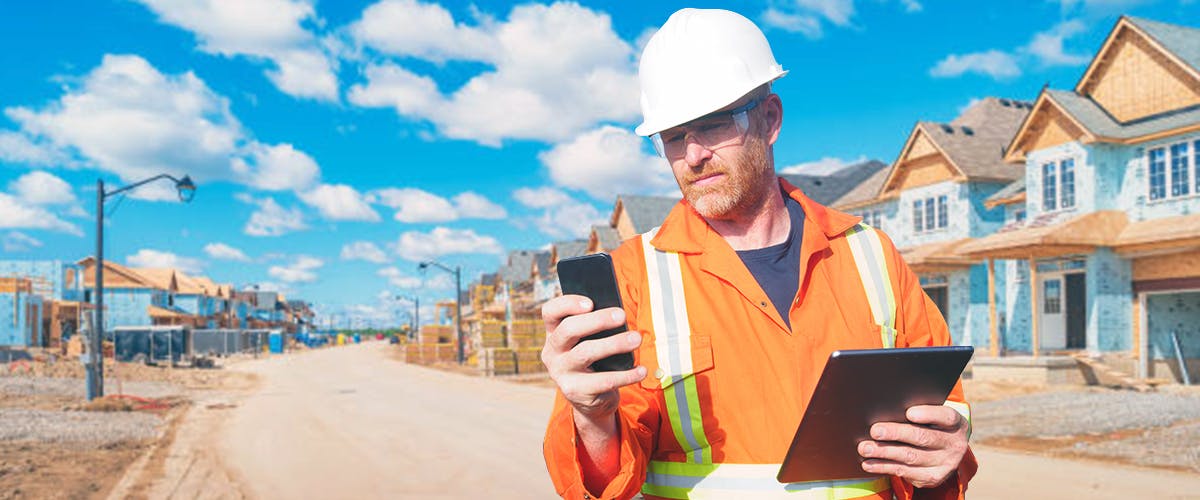 Construction worker looking at iPhone at a construction site