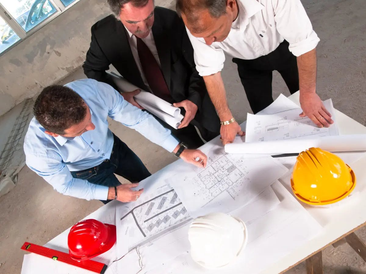 Three construction executives looking at an drawings 1200x900