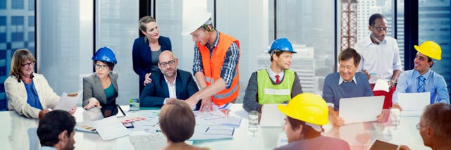 Construction workers at a table talking and looking at drawings 1200x400