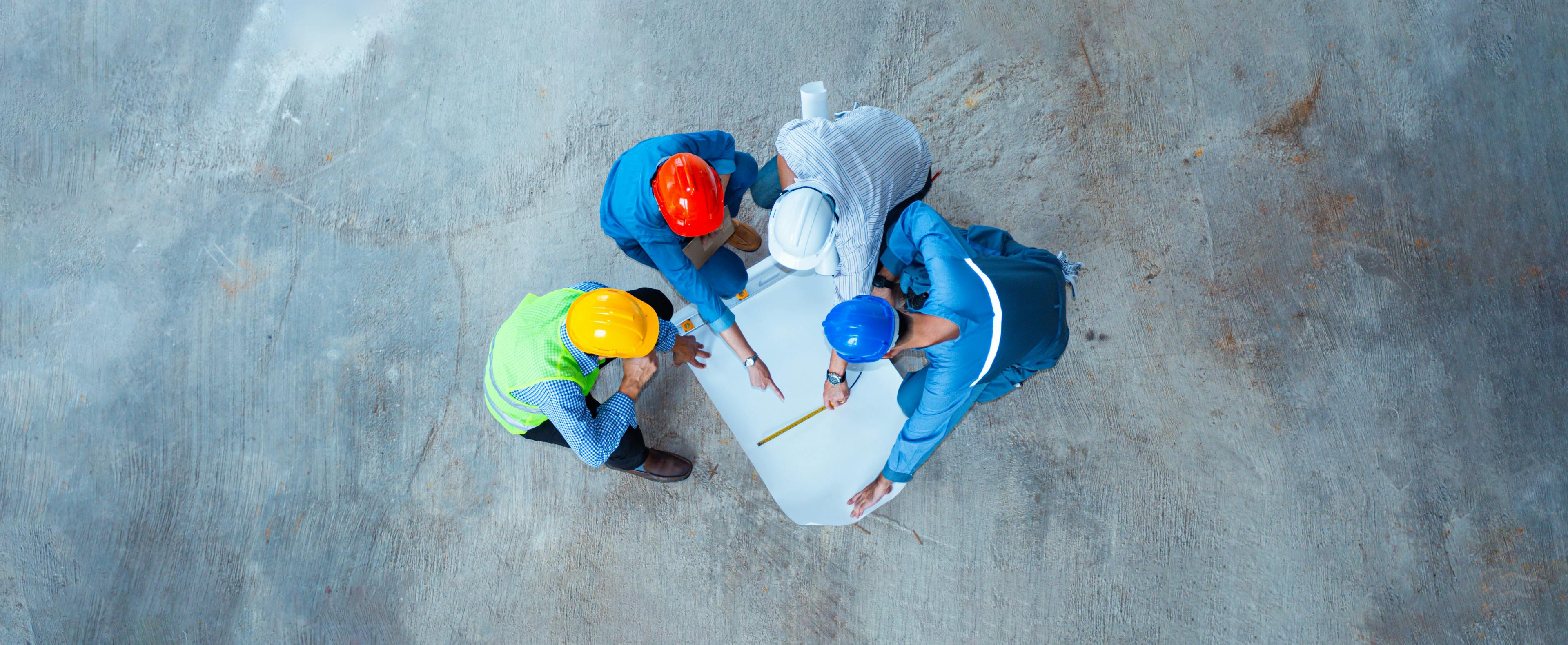 Over head shot of four construction workers standing looking at a drawing